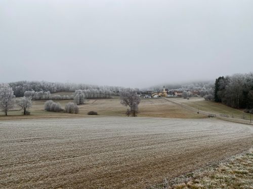Free Serene frosty winter landscape with a distant village under a cloudy sky. Stock Photo