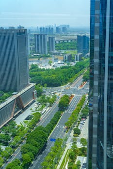 A vibrant aerial view of Hangzhou's CBD with roads and skyscrapers under the summer sun.