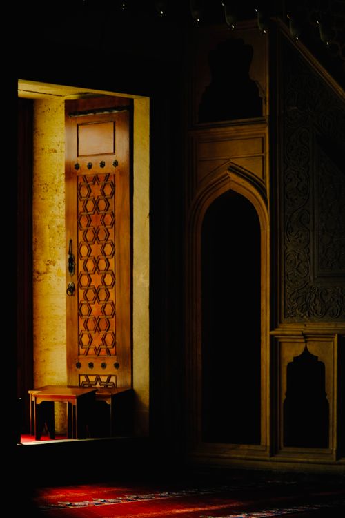 Free A warm, dimly lit scene highlighting an ornate wooden door and interior architecture. Stock Photo