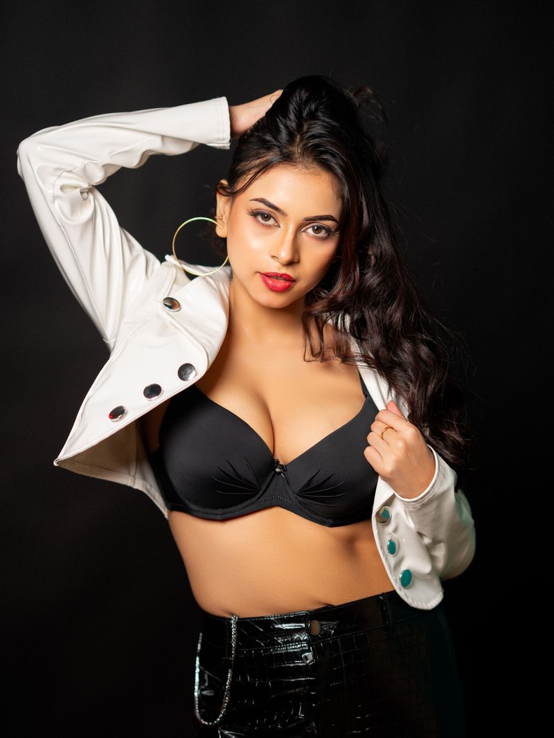 Fashionable woman posing confidently in a black outfit and white jacket.