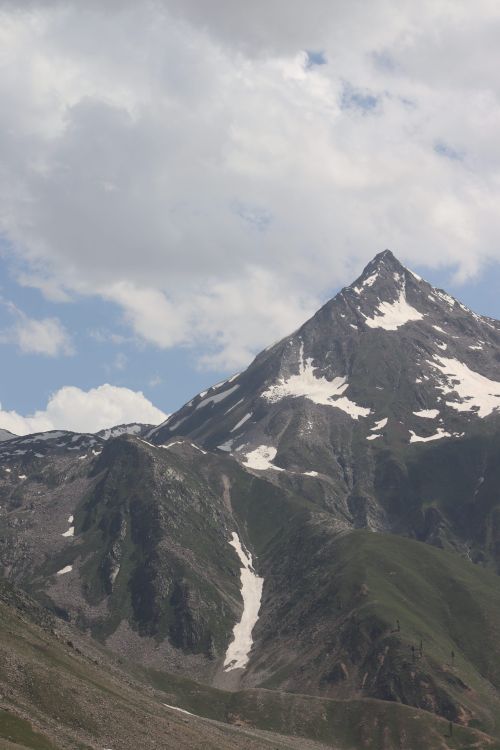 Free A stunning snow-capped mountain peak set against a cloudy blue sky, capturing nature's grandeur. Stock Photo