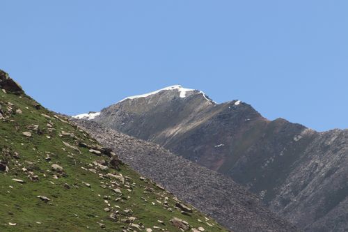 Free A serene mountain landscape featuring a snow-capped peak under a bright blue sky. Stock Photo