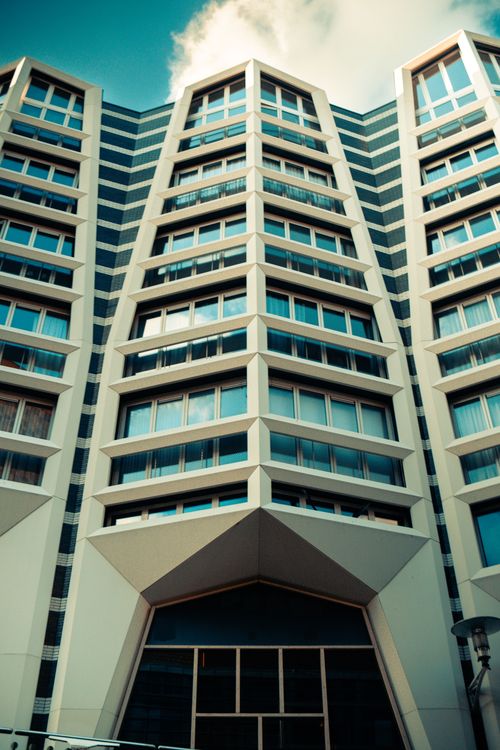Free Low-angle view of a modern architectural building with blue sky backdrop, showcasing geometric patterns and symmetry. Stock Photo