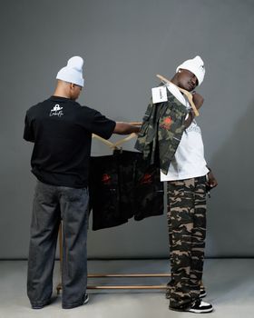 Urban streetwear fashion display with two models showcasing camouflage designs.