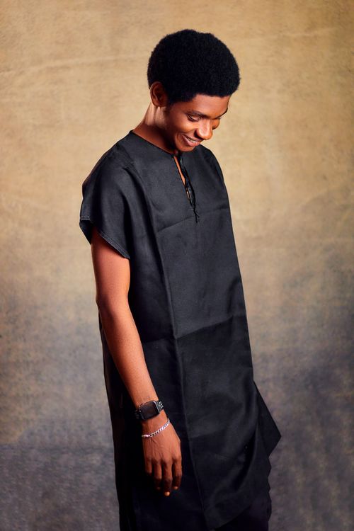 Free A young man smiling and looking down, wearing traditional black attire. Stock Photo