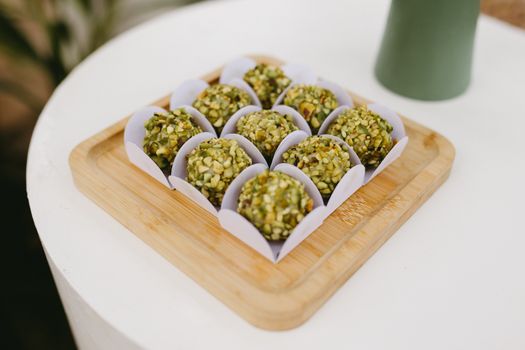 Delicious pistachio covered sweets elegantly arranged on a wooden tray, perfect for celebrations.