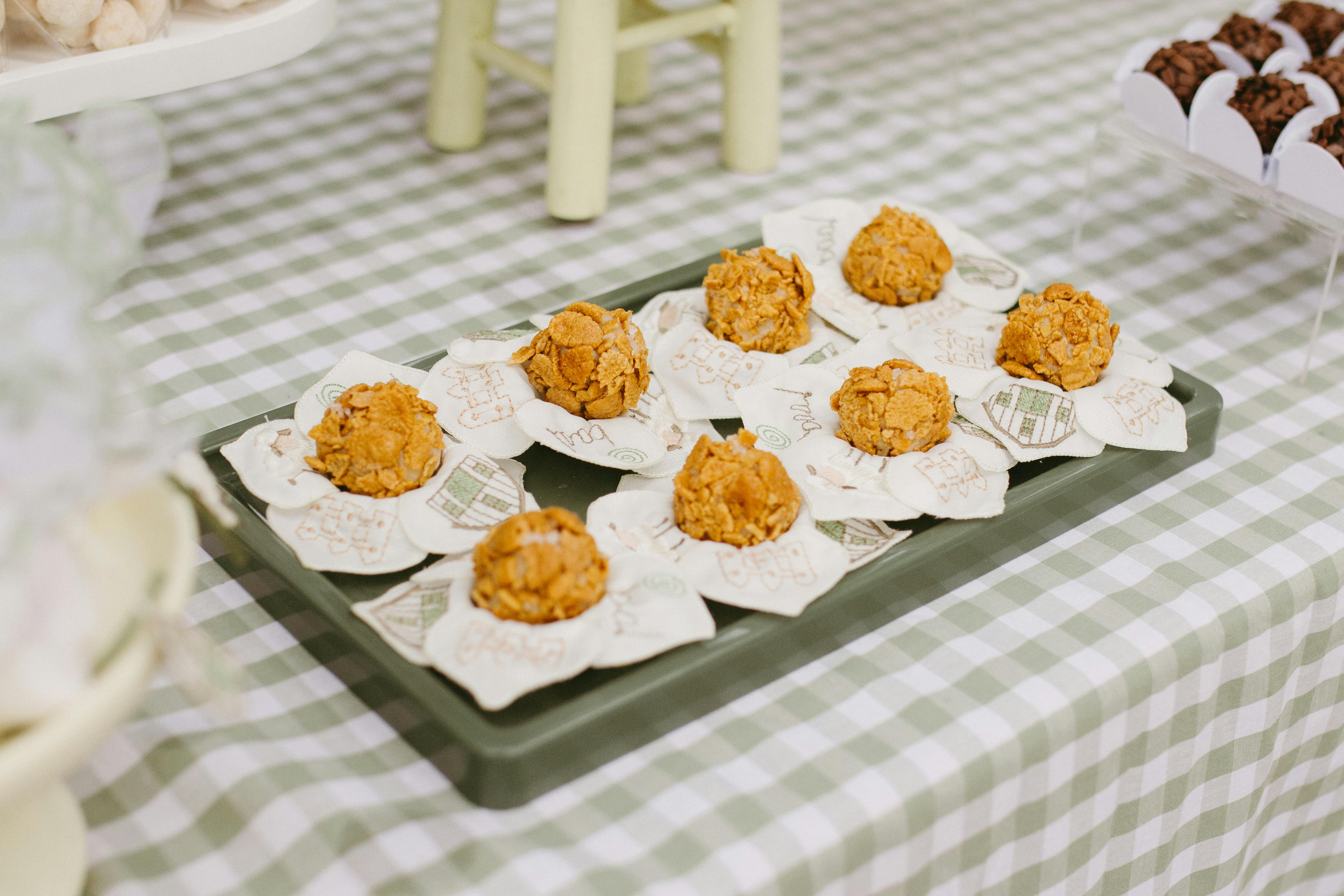 A close-up of rustic desserts on a green tray, set on a checkered tablecloth, perfect for celebrations.