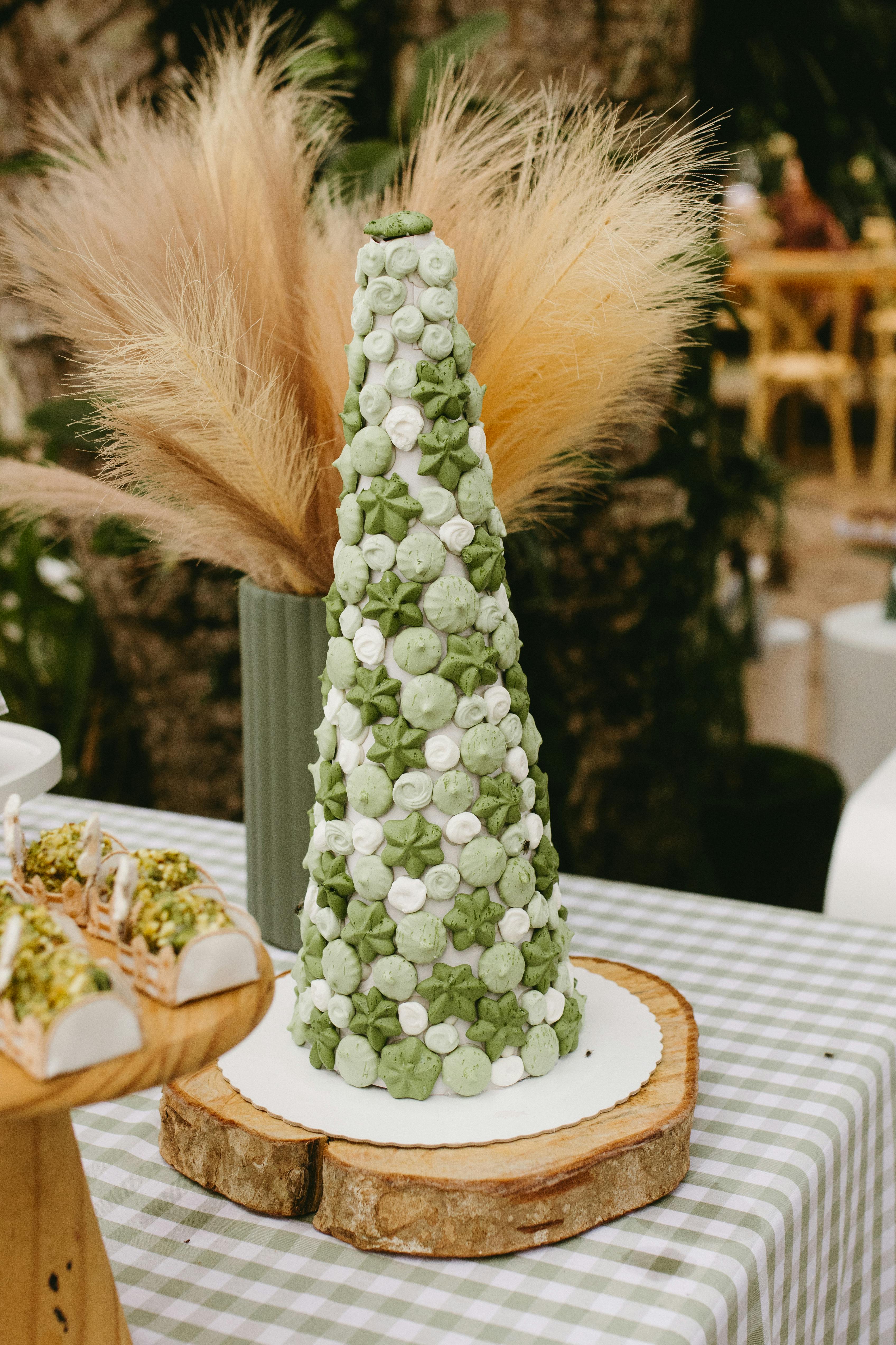 Elegant green macaron tower with floral arrangement on outdoor table setting, perfect for celebrations.