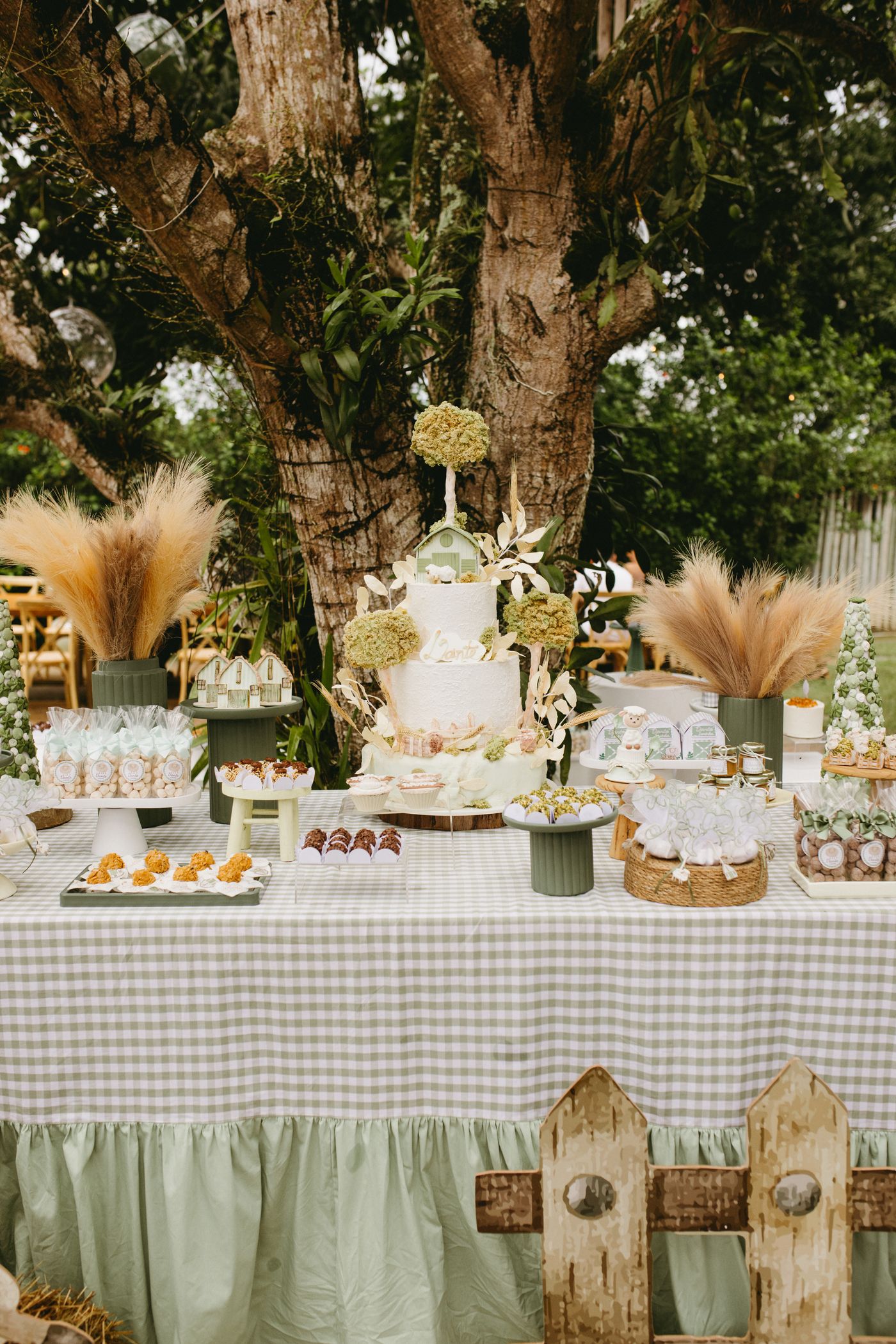 Outdoor birthday cake table beneath trees