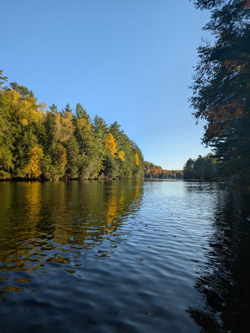 Free Serene autumn lake with vibrant fall foliage under a clear blue sky, offering a tranquil escape. Stock Photo