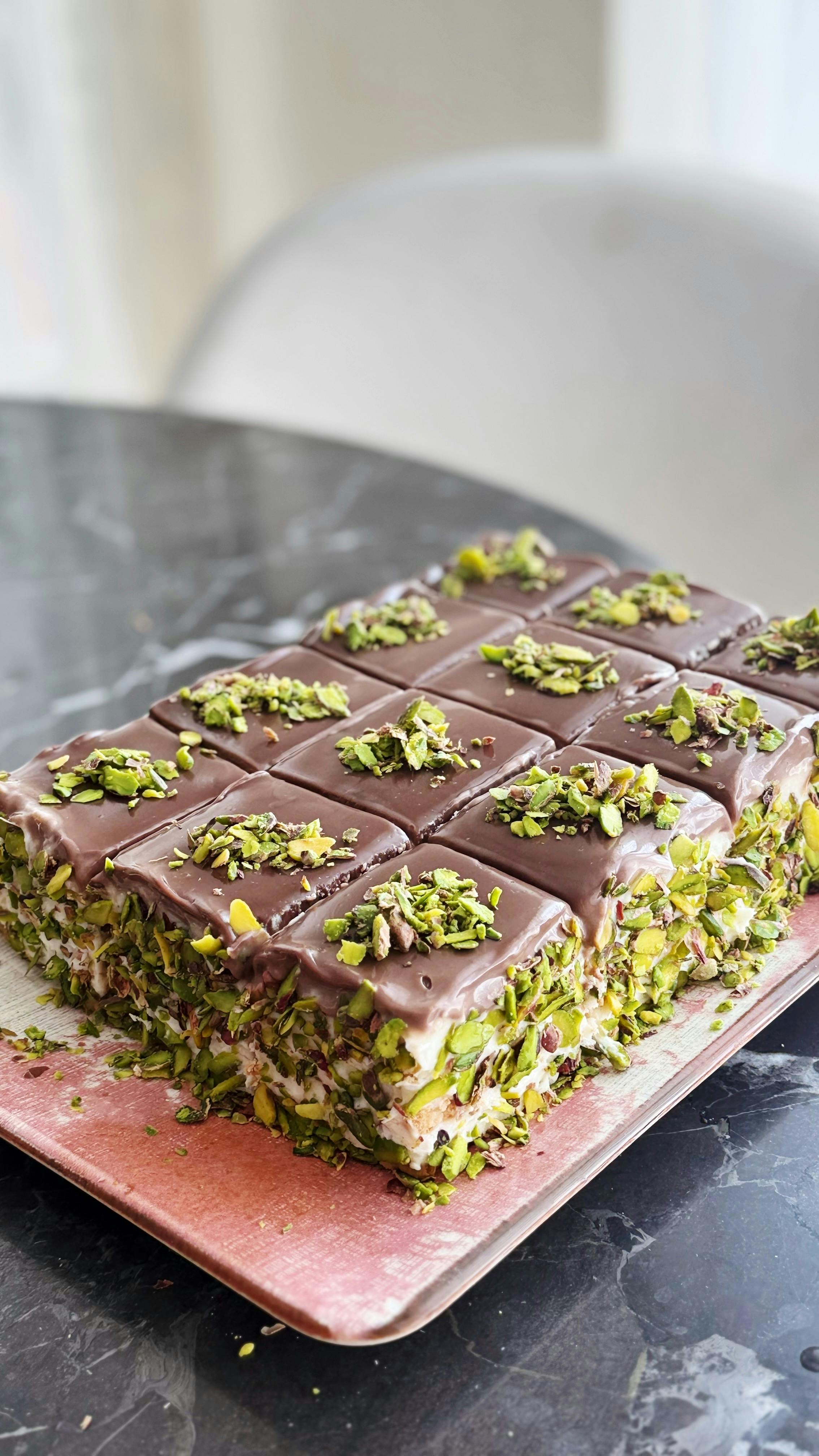 A mouth-watering pistachio chocolate dessert with rich layers and chopped pistachio topping.