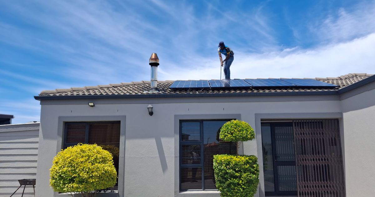 Arbeiter auf einem Wohnhausdach mit Solarmodulen – Arbeiten in Höhe erfordern Absturzsicherung