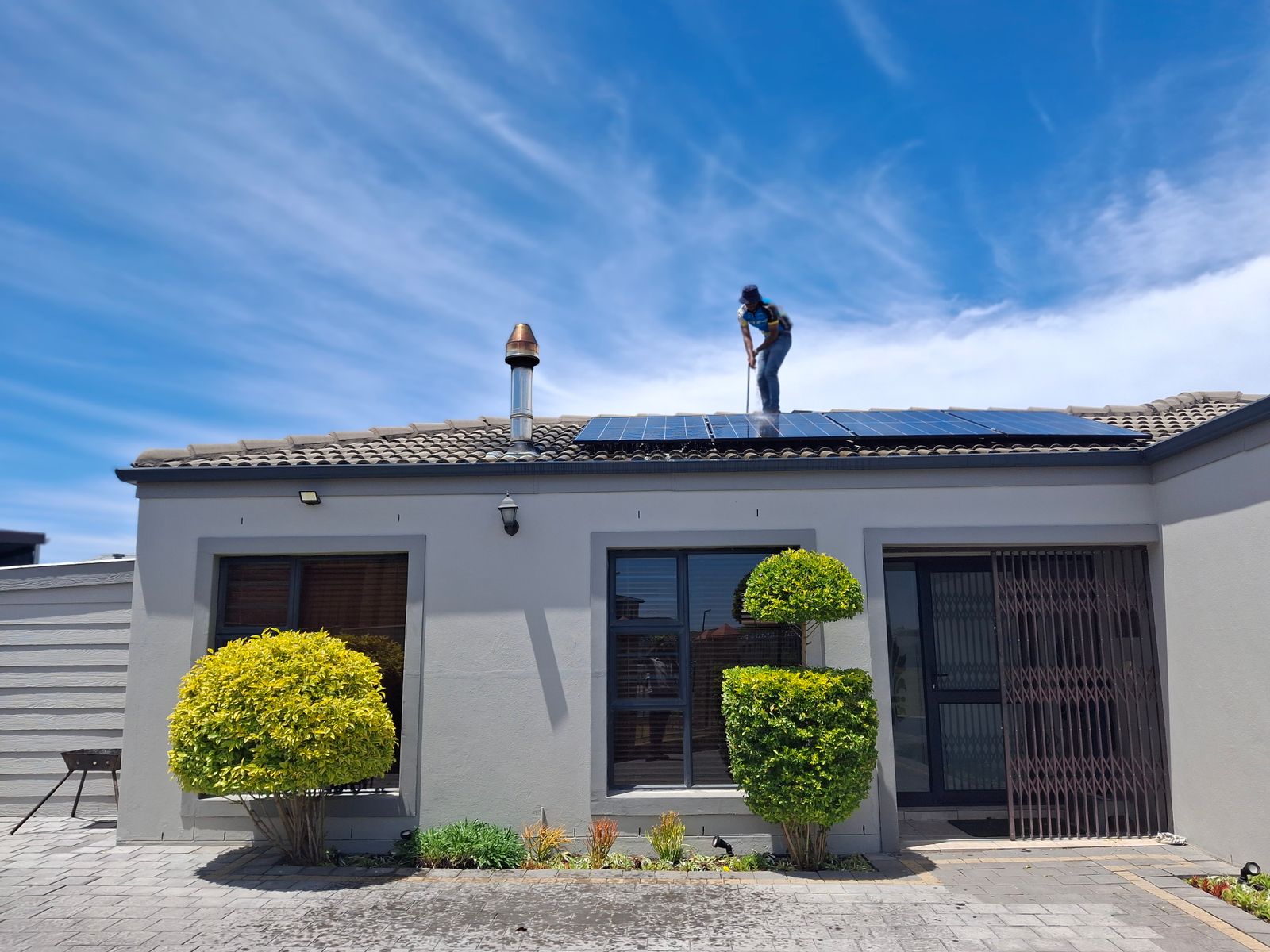 Monteur installiert Solarmodule auf einem modernen Hausdach unter blauem Himmel