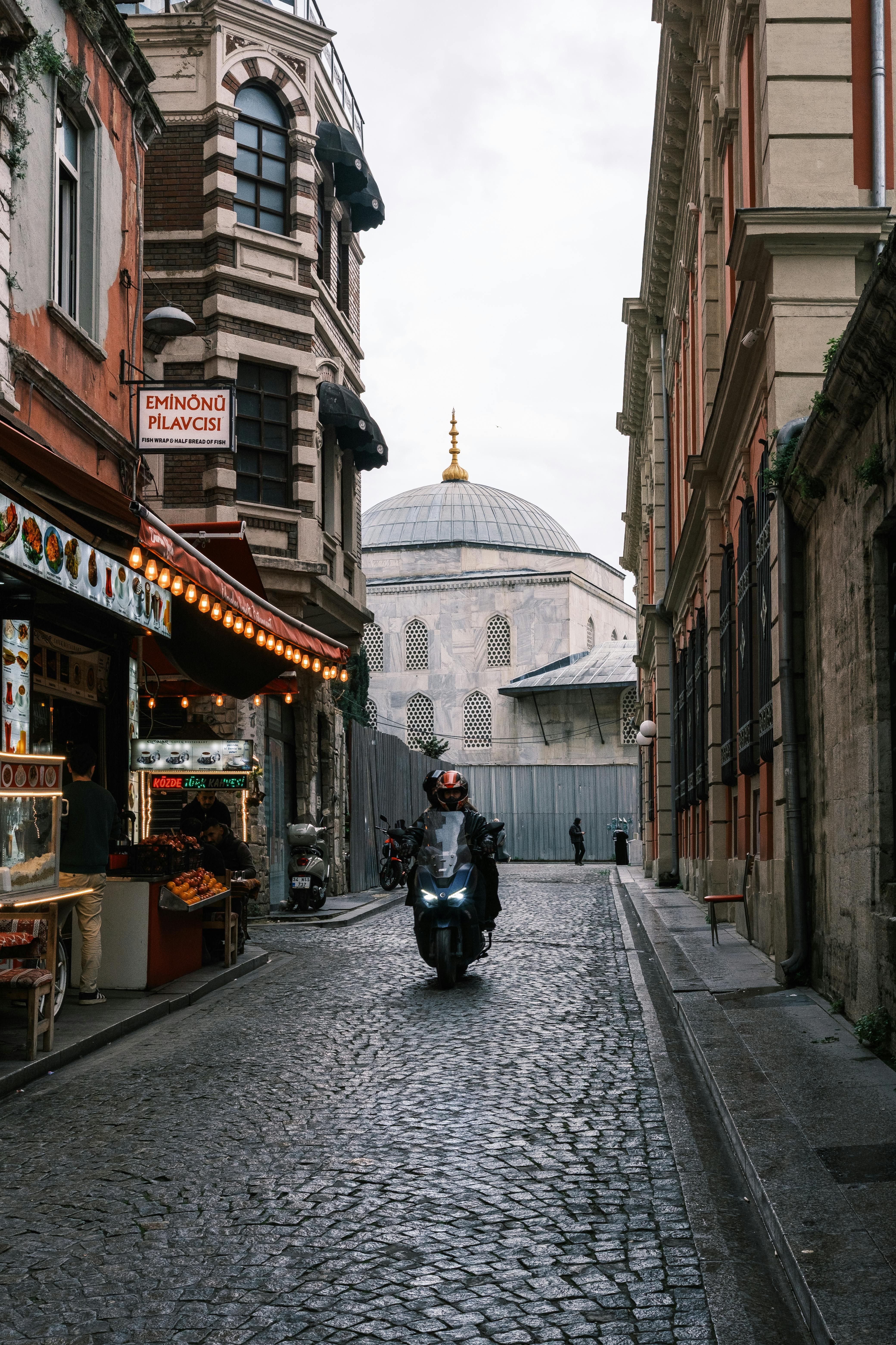 Motorcycle rider on a cobblestone street in Istanbul near historic architecture. Urban life scene.