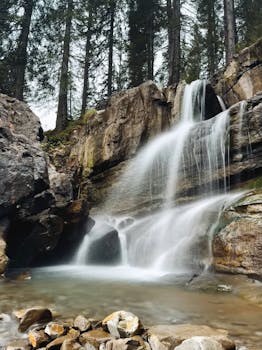 Majestic waterfall cascading through rocky forest setting, serene natural beauty.