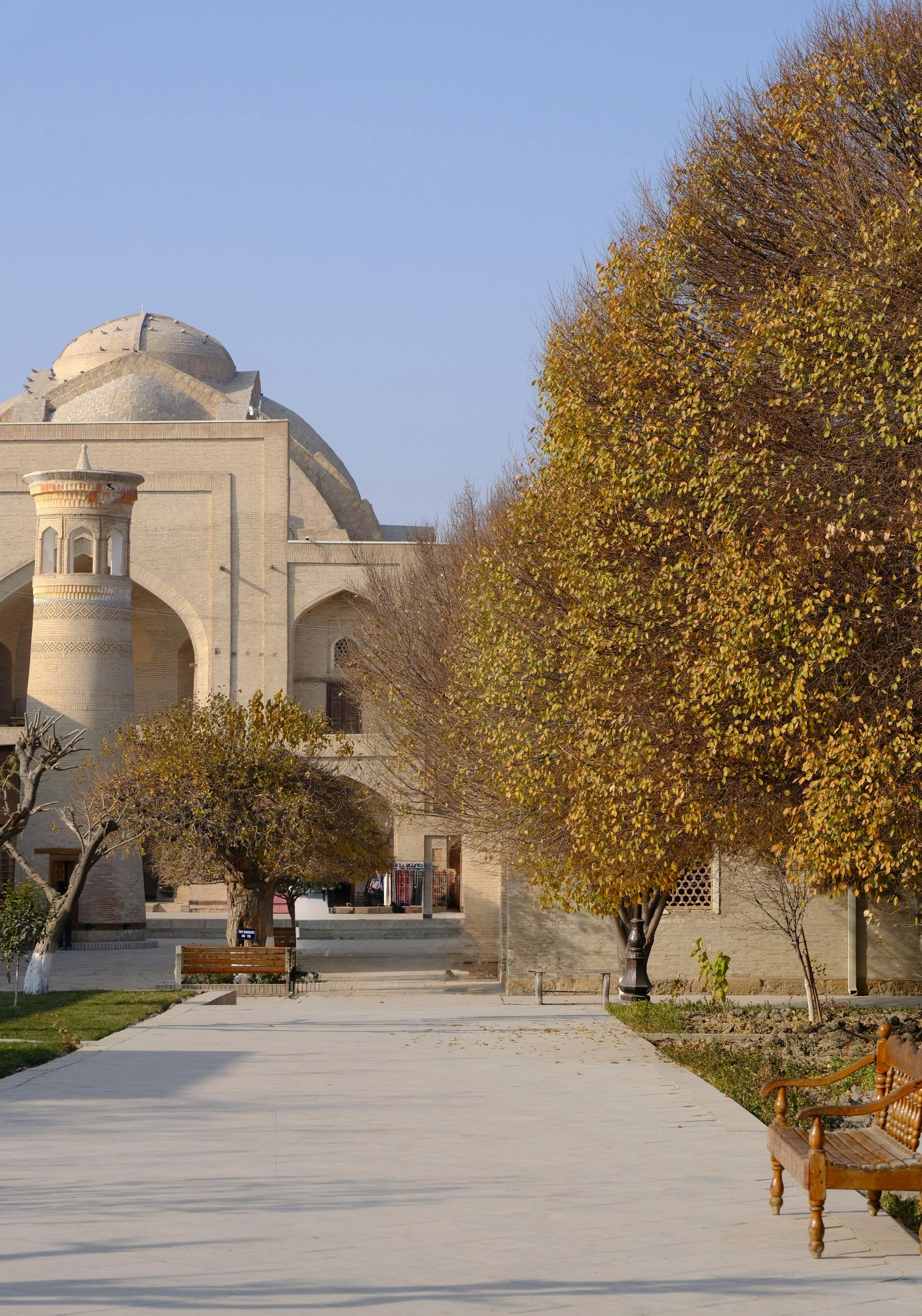 A historic building with a dome amidst autumn trees and benches in a courtyard.