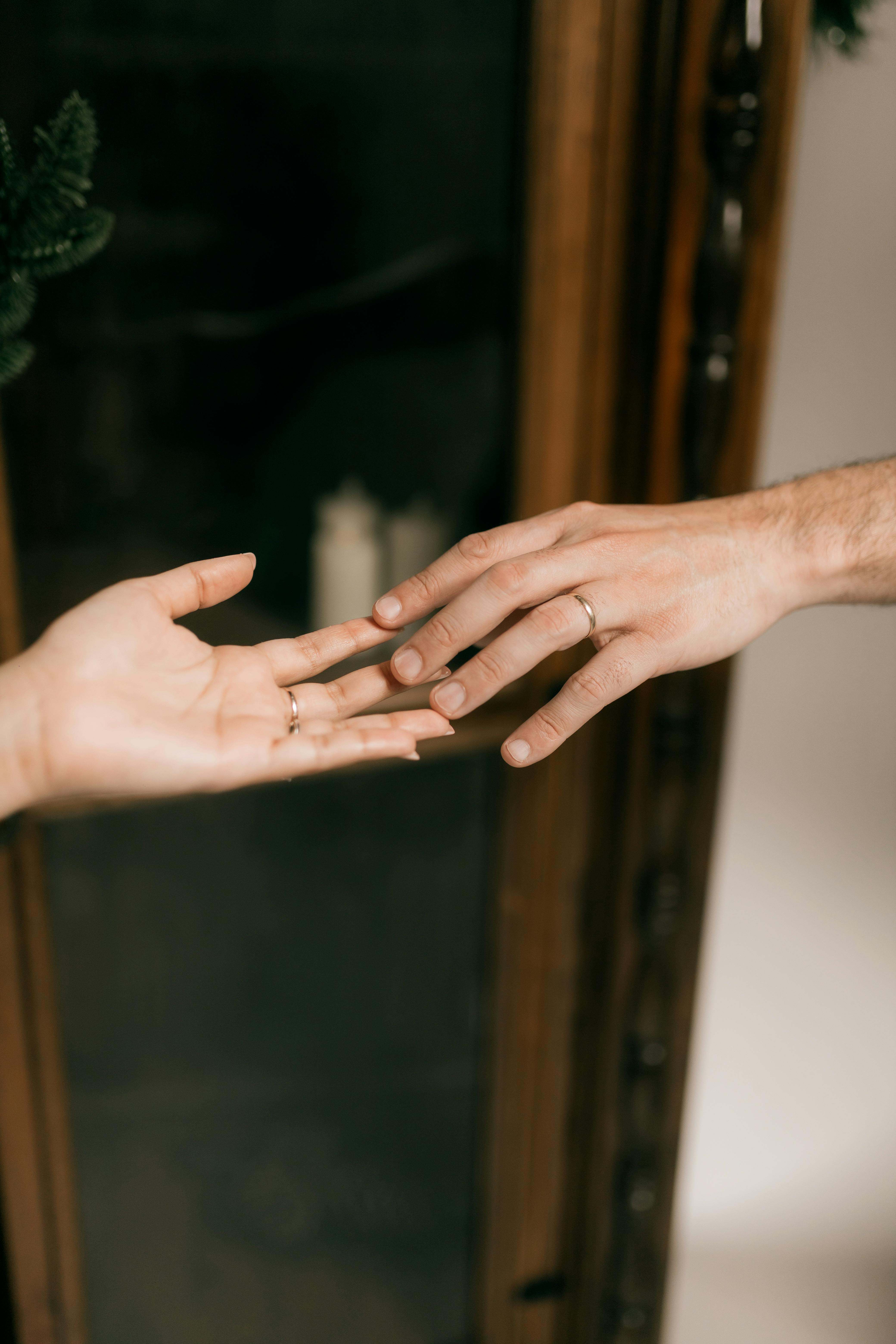 A close-up view of two hands reaching towards each other, symbolizing connection and intimacy.
