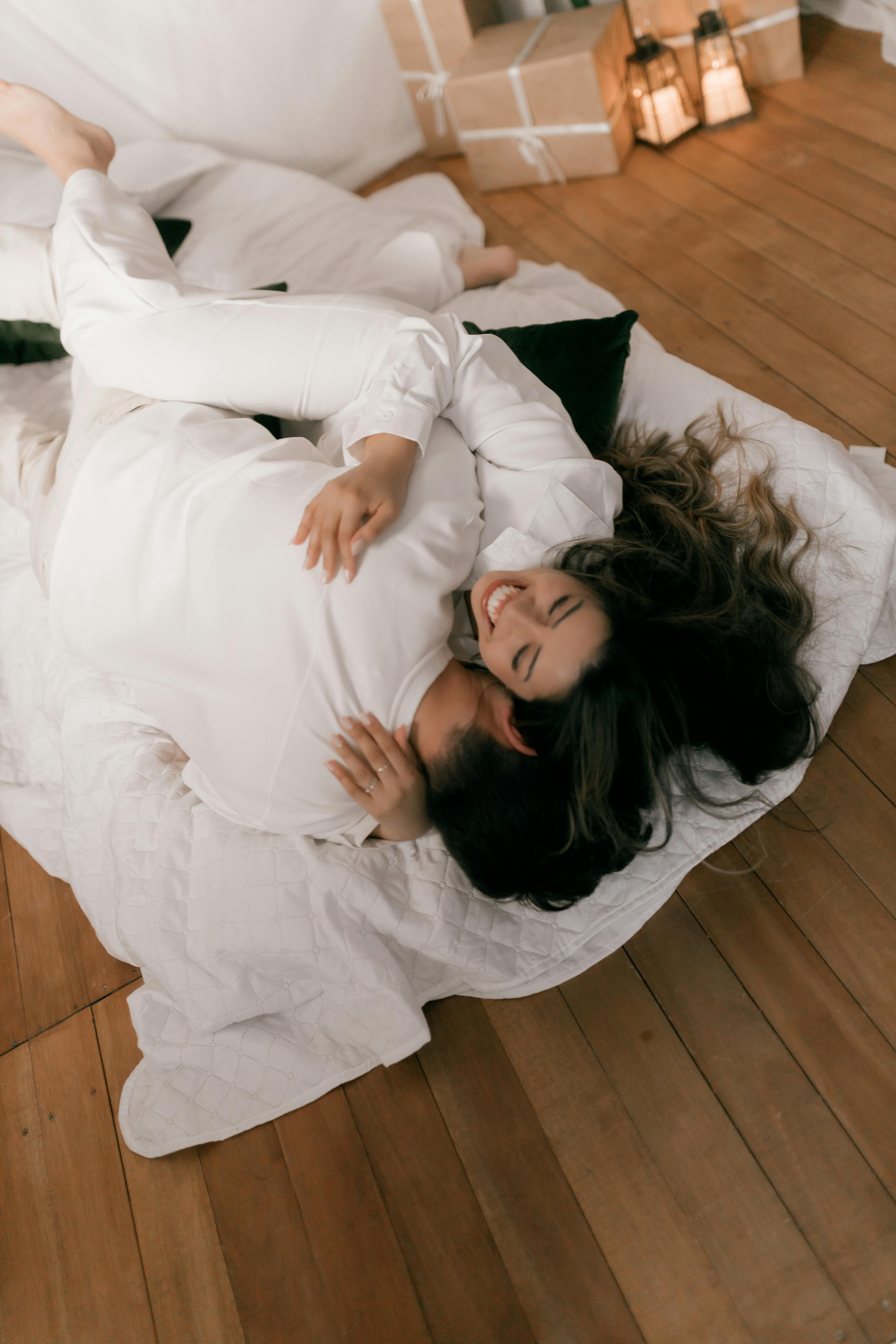 A joyful couple embracing on a bed indoors, creating a warm and cozy atmosphere.