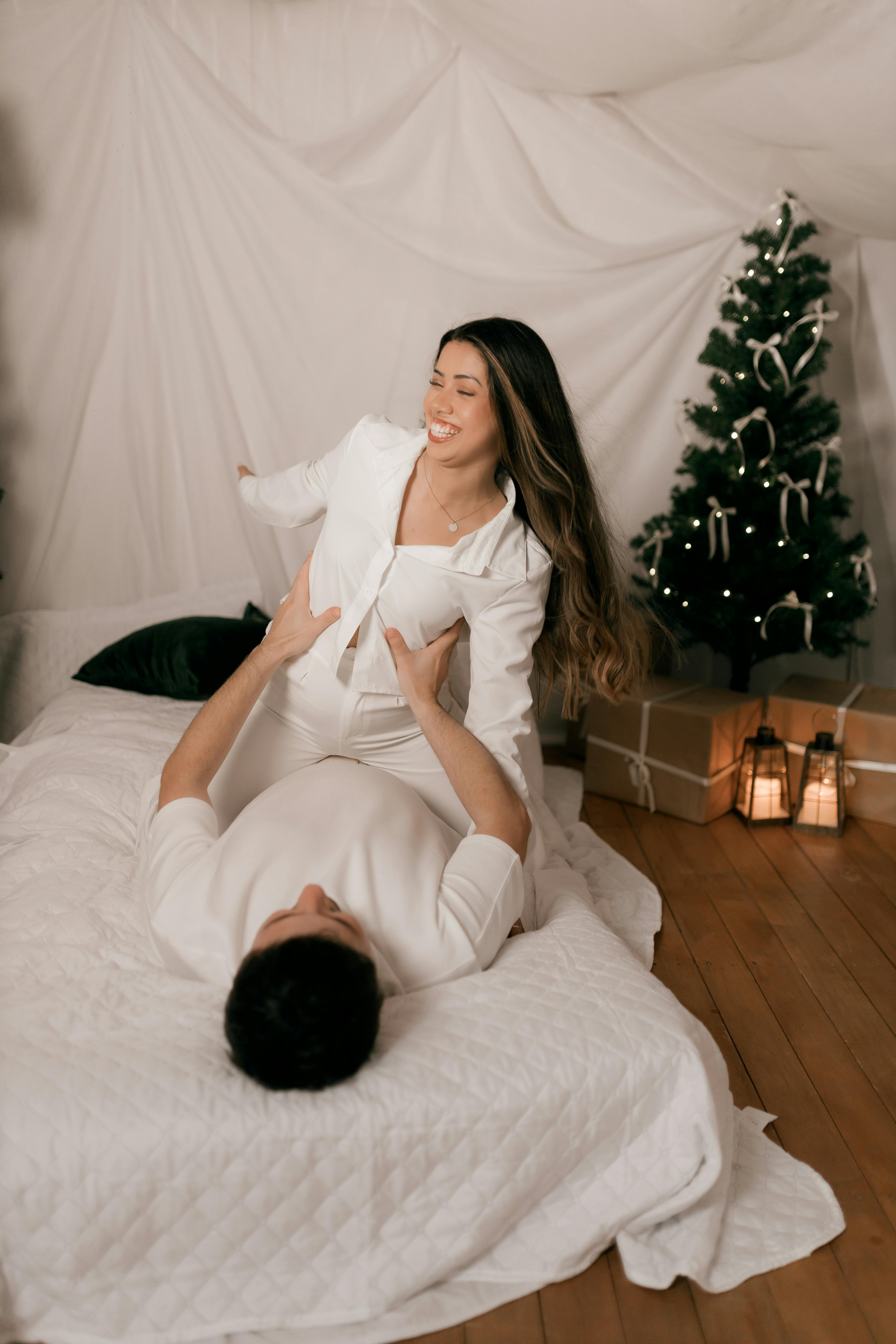 Couple enjoying a cozy indoor Christmas setting, playful and warm atmosphere.