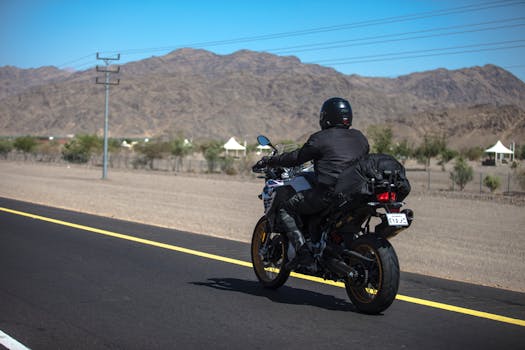 Motorcyclist rides along a scenic desert highway, framed by arid mountains. Adventure and travel concept.