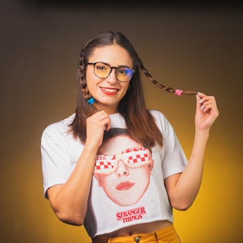 Smiling woman with braided hair wearing stylish glasses and trendy shirt in a vibrant portrait shot.