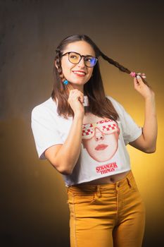 Smiling woman with unique glasses and braided hair in colorful attire, exuding joyful vibes.
