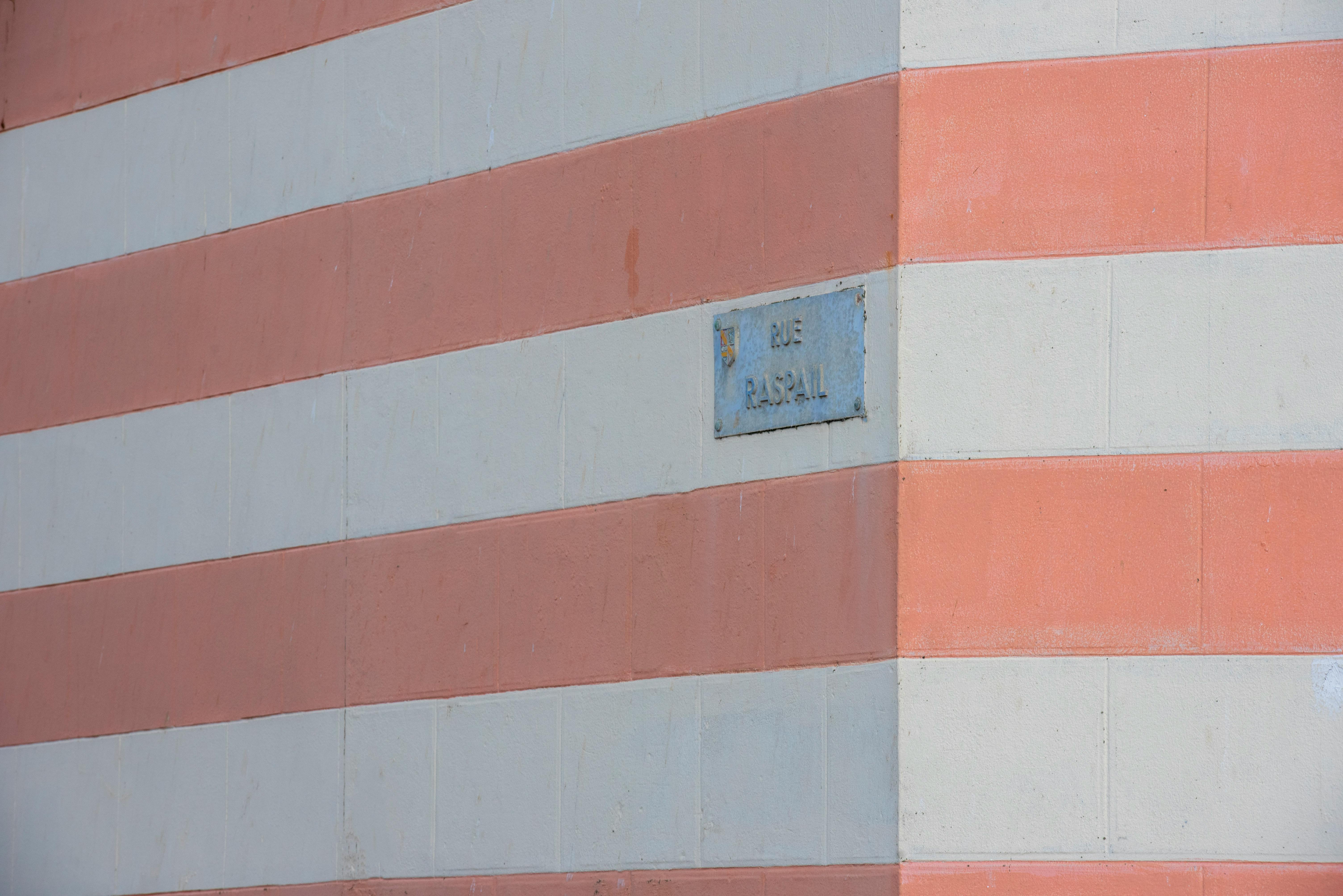 Close-up of a striped wall featuring a street sign labeled Rue Pascal.