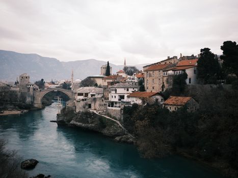 Charming view of Mostar's Old Bridge and historic buildings along the Neretva River.