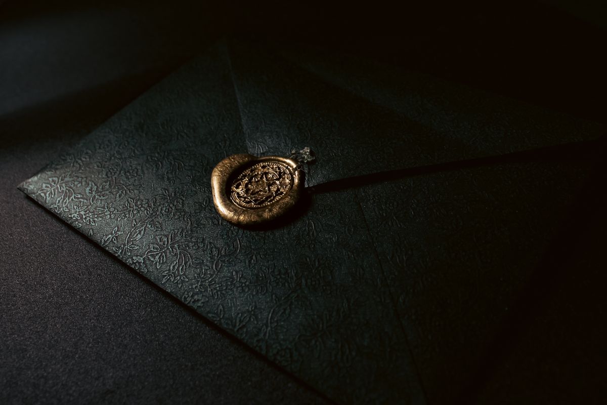 Black embossed envelope closed with a wax seal — photo by Senna Doe on Pexels