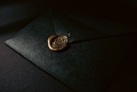Black embossed envelope closed with a wax seal — photo by Senna Doe on Pexels