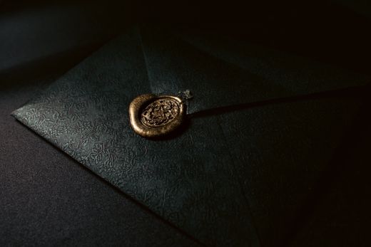 Embossed dark envelope with a wax seal — photo by Senna Doe on Pexels