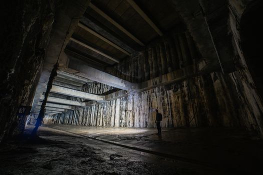 A lone explorer in a dimly lit, abandoned underground structure.