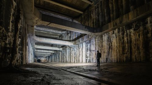 Free A lone figure explores a vast, cavernous underground space with geometric architecture. Stock Photo