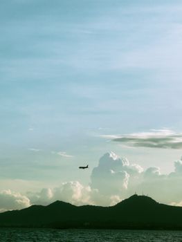Airplane flying over mountains with scenic clouds at sunset, creating a tranquil and scenic scene.