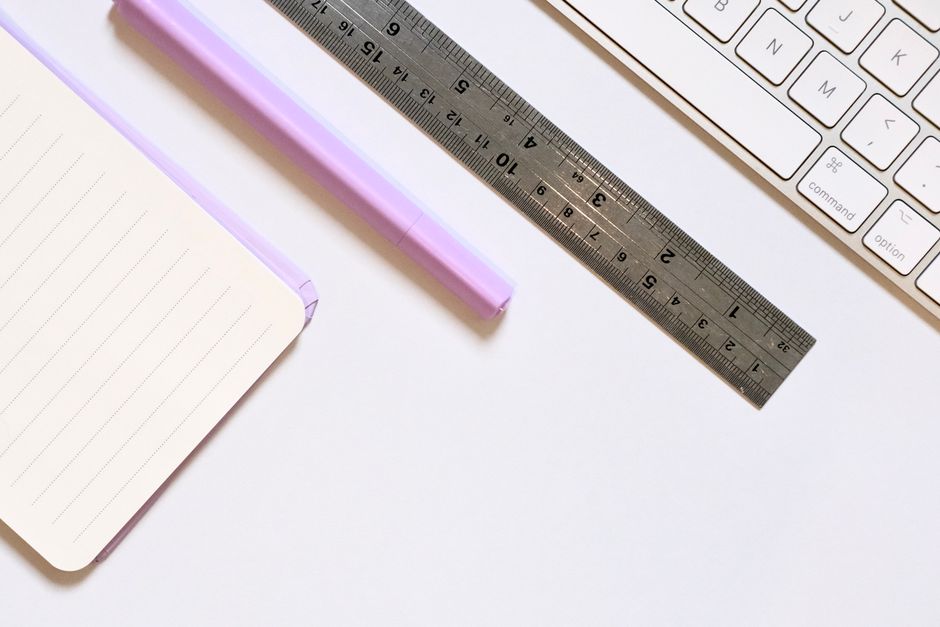 A clean desk setup with a notebook, pen, ruler, and keyboard for productivity and organization.
