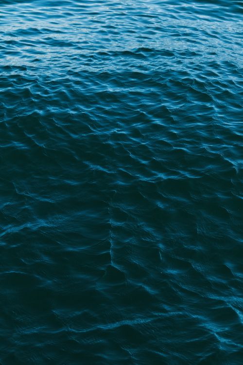Free Serene turquoise waves gently ripple across the ocean surface, exuding peace and tranquility. Stock Photo