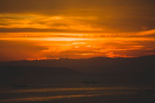 Free Vibrant orange sunset casting warm light over serene ocean landscape. Stock Photo