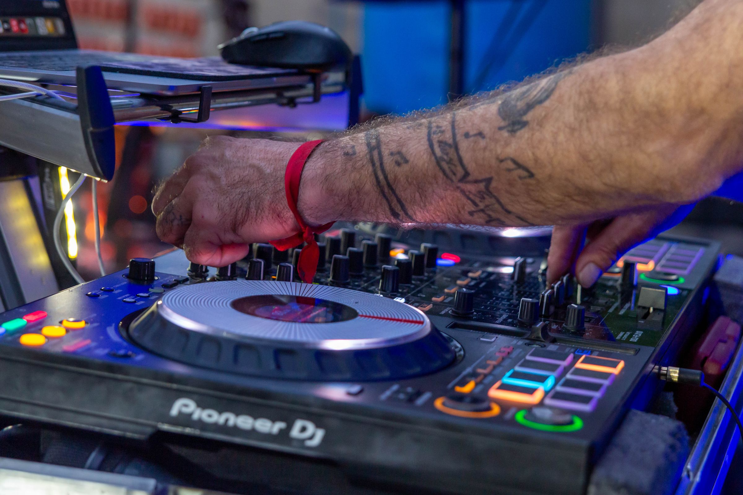 DJ hand mixing music on Pioneer turntables with vivid stage lighting at a live event
