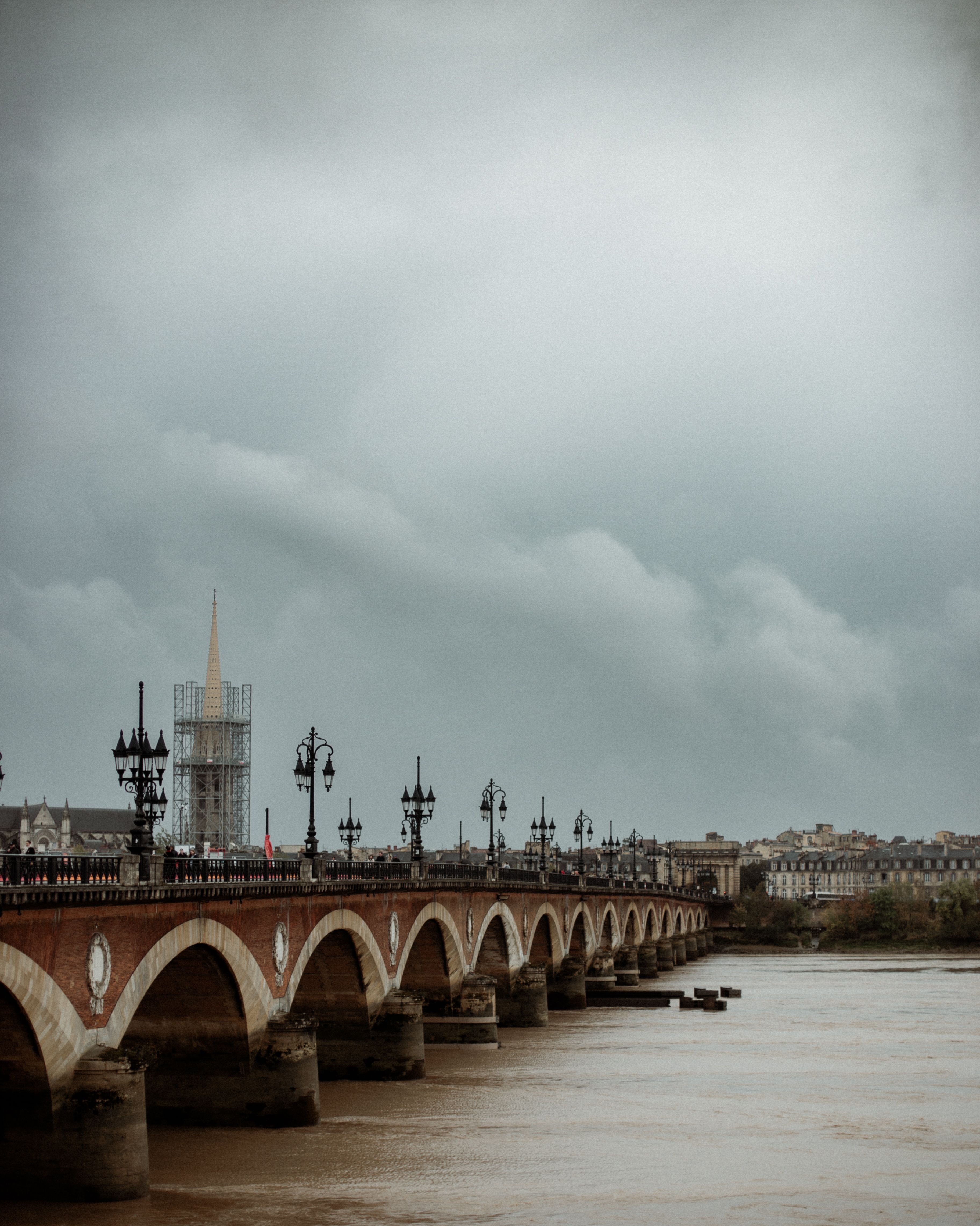 Fotomural Vista panorámica del Pont de Pierre sobre el río Garona en Burdeos bajo un cielo nublado.