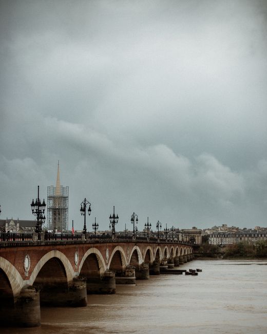 Fotomural Vista panorámica del Pont de Pierre sobre el río Garona en Burdeos bajo un cielo nublado.