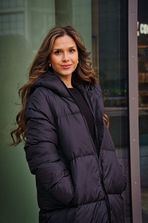 Free A fashionable woman in a black coat poses confidently on a winter day in Berlin. Stock Photo