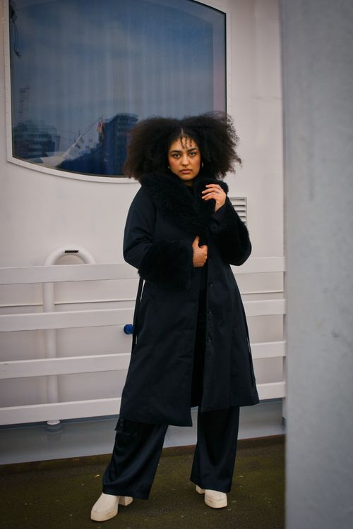 Free Stylish woman in a black coat stands confidently outdoors, blending fashion with city vibes. Stock Photo