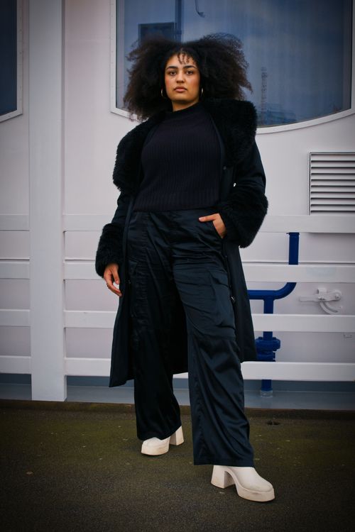 Free Confident woman wearing black coat and pants poses outdoors in Hamburg. Stock Photo