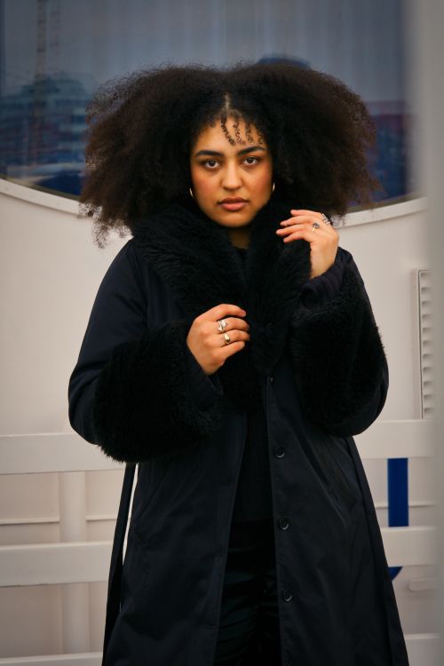 Free Confident woman in a black coat posing outdoors in Hamburg, Germany. Stock Photo