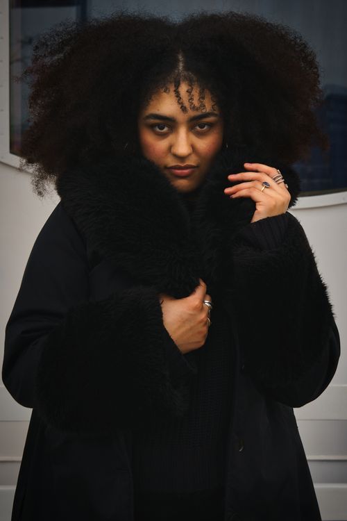 Free Stylish portrait of a woman in a black coat with natural hair and confident expression. Stock Photo