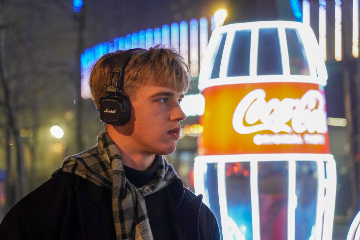 Man enjoying music in front of neon lights at night.