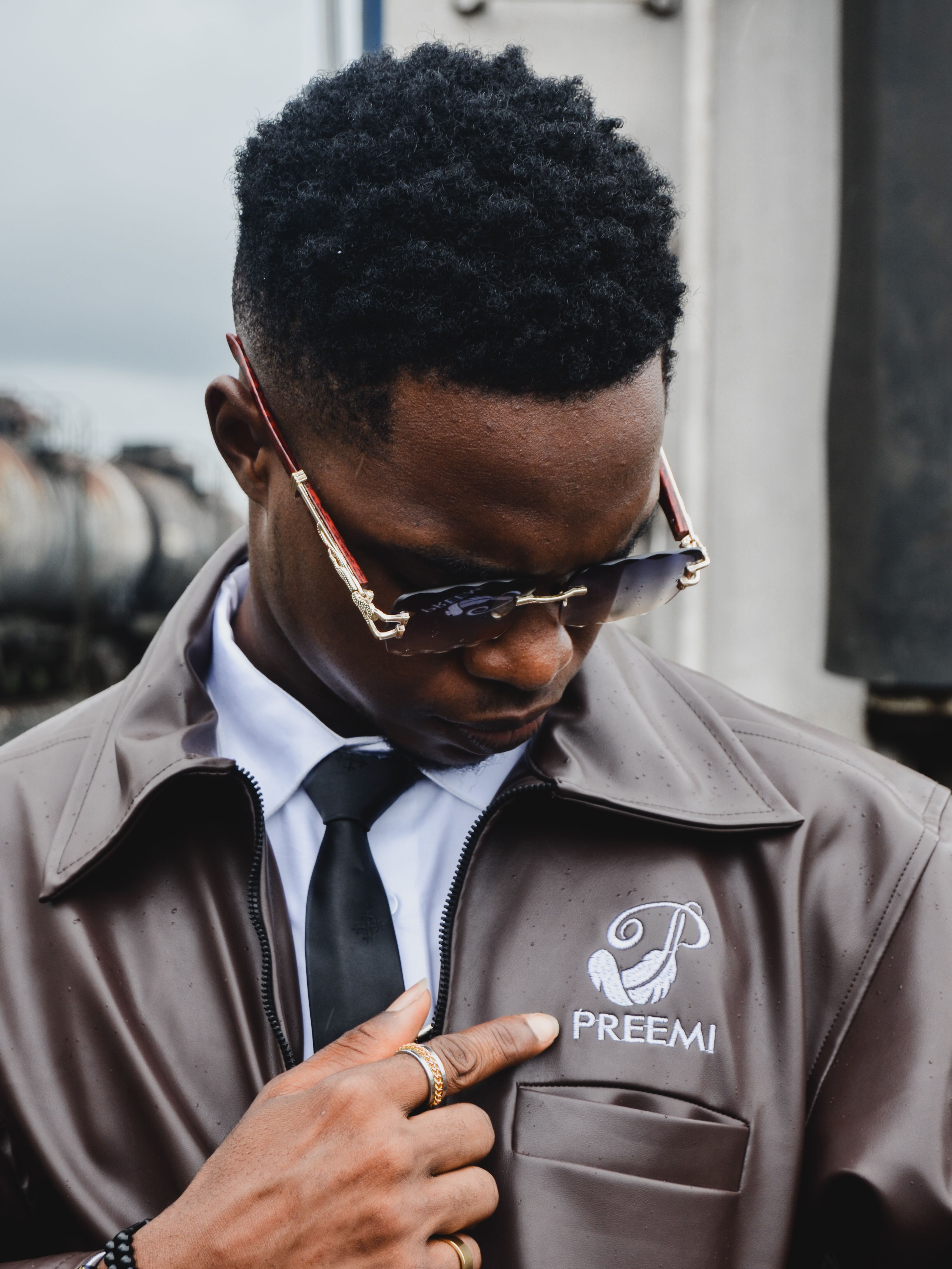 Fashionable man wearing sunglasses and a designer jacket with logo in Port Harcourt, Nigeria.