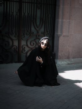 Stylish woman in black attire posing by an ornate gate in Mexico City.
