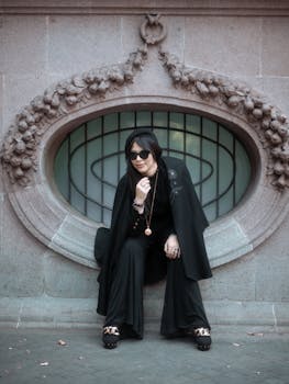 Elegant black-clad model poses in Gothic style against a stone backdrop in Mexico City.