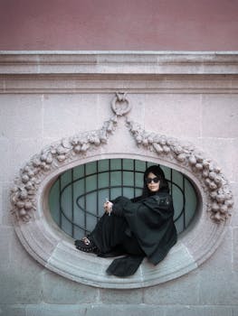 Stylish portrait of a woman in black attire sitting in an ornate window in Mexico City.
